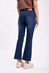Pantalón de jean azul oscuro, tiro alto, corte cropped flare con terminación desflecada.
