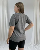 Remera gris de corte clásico con estampa de flor de hibisco fucsia y texto en gris.