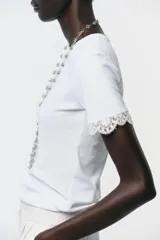 Camiseta blanca de algodón con cuello redondo y mangas cortas con detalle de encaje negro.
