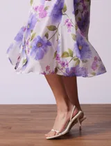 Vestido midi de gasa estampada con flores violetas y verdes, escote en V, abertura central con botones, cintura con lazo de ajuste y forro interno a tono.