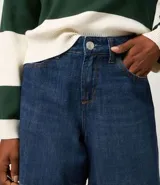 Bermuda de jeans azul oscuro, con trabillas en la cintura, bolsillos laterales y traseros, y cierre de botón y cremallera.