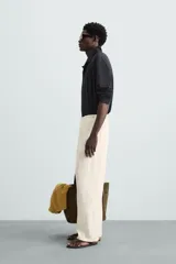 Pantalón de lino color crudo, de corte ancho, con cintura elástica ajustable con cordón, bolsillos laterales y trasero.