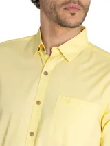 Camisa casual de hombre RKF Galiton, color amarillo claro, de manga larga ajustable con botones de madera. Confeccionada en popelina 100% algodón orgánico, con bolsillo de pecho con logo bordado y protección UV 20+.