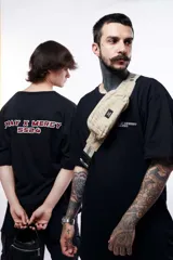 Remera negra oversize de manga corta, con estampa en la espalda con la frase "PRAY X MERCY SS24" en rojo y blanco.