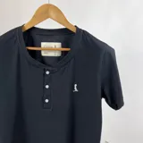 Remera negra de manga corta con cuello redondo y botonera frontal.