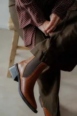 Botines Chelsea color beige con elásticos laterales negros, punta cuadrada, detalle de hebilla lateral y tacón bloque bajo.