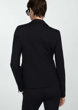 Blazer negro de corte entallado, con solapas de muesca, cierre de un botón, dos bolsillos de solapa y puños abotonados.