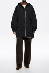 Abrigo largo negro de corte línea A, confeccionado en tejido técnico acolchado con patrón de costuras en zigzag. Posee cuello subido con capucha integrada y cordones a contraste, cierre frontal de botones de presión ocultos, bolsillos de vivo y puños anchos elastizados.