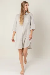 Vestido camisero negro de lino con botones, mangas 3/4 con trabilla y bolsillo de parche en el pecho con bordado de letras. Tiene aberturas laterales en el ruedo y costuras a contratono en color crudo.