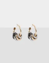 Aros tipo argolla dorados con dijes de arandelas en dorado, plateado y negro.