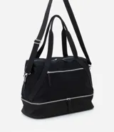 Bolso tipo maleta de tamaño grande en color negro, confeccionado en una mezcla de poliuretano y poliéster. Presenta cierres de cremallera plateados contrastantes, un bolsillo frontal con cierre y un compartimento inferior independiente con cierre. Incluye asas de mano dobles y una correa de hombro larga, ajustable y extraíble.