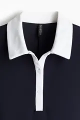 Vestido corto azul marino con cuello blanco, tapeta de botones y pollera acampanada.