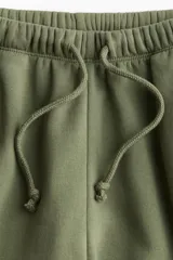 Pantalón de jogging verde oliva, de corte amplio, con cintura elástica ajustable con cordón y bolsillos laterales.