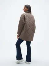 Campera negra de pana con diseño acolchado en forma de rombos, cuello camisero, cierre con botones a presión, bolsillos de parche con solapa en el pecho y bolsillos laterales.