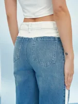 Pantalón de jean azul con cintura blanca y raya blanca lateral.