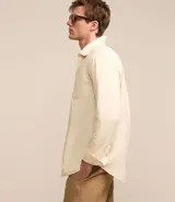 Camisa de hombre de corte regular, color borgoña, confeccionada en tela Oxford con efecto jaspeado. Tiene cuello inglés, abotonadura frontal, mangas largas con puños abotonados y bolsillo de parche en el pecho.