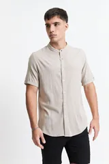 Camisa blanca de manga corta con cuello mao y doblez en las mangas.