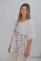 Blusa blanca con estampado de hojas marrones, de corte holgado y mangas cortas.