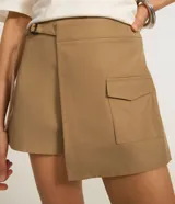 Bermuda color beige de corte sastrero, con hebilla en la cintura, diseño cruzado y bolsillos delanteros.