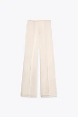 Pantalón de vestir color crema, de tela satinada, tiro alto y corte palazzo.