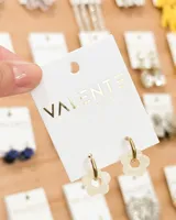 Aros colgantes con aro dorado y dije de flor calada color crema. El aro es de acero y la flor de acrílico.