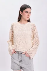 Sweater de crochet color crudo con mangas largas acampanadas.
