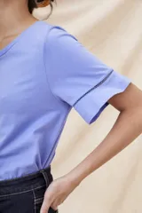 Remera blanca de algodón con cuello redondo y mangas cortas con volado y detalle de puntilla calada.