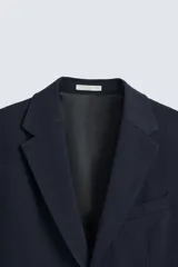 Blazer slim fit color azul marino confeccionada en tejido con 17% de lana. Cuello con solapas de muesca. Manga larga acabada en puño con detalle de botones. Bolsillo de vivo en pecho y de solapa en cadera. Detalle bolsillo interior. Bajo con aberturas en espalda. Cierre frontal con botones.