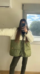 Campera con parte superior de corderito color blanco y parte inferior capitoneada a rayas color verde militar. Tiene botones a presión y corte oversize.