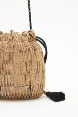 Cartera de noche tipo bolso redondo, confeccionada con lentejuelas y canutillos dorados. Cuenta con cordón de ajuste con borlas negras y correa al tono con apliques de canutillos.