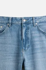 Pantalón de jean celeste de corte slim fit y tapered, con cinco bolsillos, efecto lavado y cierre frontal con cremallera y botón.