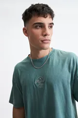 Remera azul de manga corta con cuello redondo, corte holgado y logo bordado en el pecho.