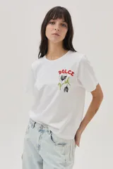 Remera blanca de algodón con cuello redondo y mangas cortas. Estampado en el frente con la palabra "Dolce" en rojo y un diseño floral en negro y verde.