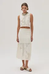 Falda midi color crudo, tejida de punto calado con diseño de flores. Cuenta con elástico y lurex en la cintura.