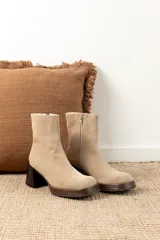 Bota corta de gamuza color beige claro, con caña ajustada y taco cuadrado de madera oscura.