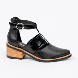 Zapato de cuero negro con detalle de charol, taco de madera con folia en cuero de 5cm, cierre YKK en talón, hebilla y elástico en el empeine.