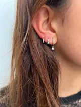 Set de tres aros de plata con incrustaciones de circonias. Incluye un aro tipo argolla con circonias, un aro con tres circonias engarzadas y un aro con un dije colgante de circonia.