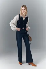 Pantalón jean de tiro medio, calce ajustado, lavado azul oscuro de look sastrero y pierna levemente acampanada con ruedo ancho.