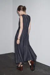 Vestido midi de denim azul oscuro, con cuello redondo y sin mangas. Corte entallado en la cintura y falda evasé. Cierre trasero con cremallera oculta.