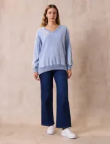 Buzo celeste de algodón con efecto lavado, escote en V, cuello, puños y ruedo acanalados y tajos laterales.
