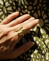 Anillo de diseño orgánico y macizo, realizado artesanalmente en bronce. Presenta una estructura abierta con dos piezas de forma irregular y textura rugosa.