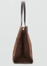 Bolso tipo shopper de piel de serraje color marrón, con diseño de paneles cosidos en el frente y bordes ribeteados en cuero liso oscuro. Posee dos asas de hombro de cuero liso oscuro y cierre de botón magnético.