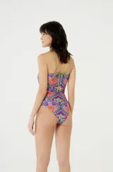 Traje de baño enterizo con estampado floral multicolor, escote strapless con abertura y tiras finas verdes cruzadas.