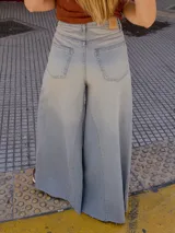 Pantalón de jean celeste de tiro medio con pierna extra ancha y caída fluida, con bolsillos delanteros y traseros, y cierre frontal con cremallera y botón metálico.