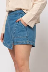 Short pollera de jean de tiro alto, color celeste, con cierre trasero invisible y detalle de bolsillos delanteros.