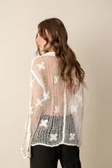 Camisa blanca de crochet con mangas largas y botones frontales.