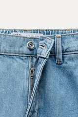 Pantalón de jean azul oscuro, corte carrot, tiro medio, largo cropped, con cintura elástica en la parte trasera, bolsillos delanteros y traseros, cierre con cremallera y botón.