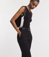 Pantalón de vestir negro de corte carrot, con cintura alta, trabillas y cinturón con hebilla metálica.