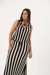 Pollera larga tejida a rayas verticales negras y beige, con pretina elástica y tajos laterales.