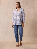 Blusa estampada con flores azules sobre fondo blanco, marca Floral & Ivy. Tiene cuello a la base con escote en V y aplique de botones. Las mangas son tres cuartos con puño y botón. Presenta tajos en las costuras laterales.